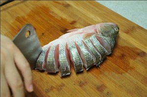 將鱸魚(yú)清洗干凈，從脊椎處切斷至腹部，腹部保留1cm左右不要切斷。