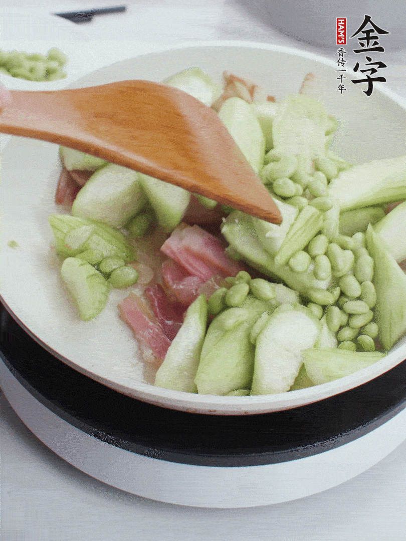 依次下絲瓜、青豆翻炒，炒至絲瓜打蔫縮小。
