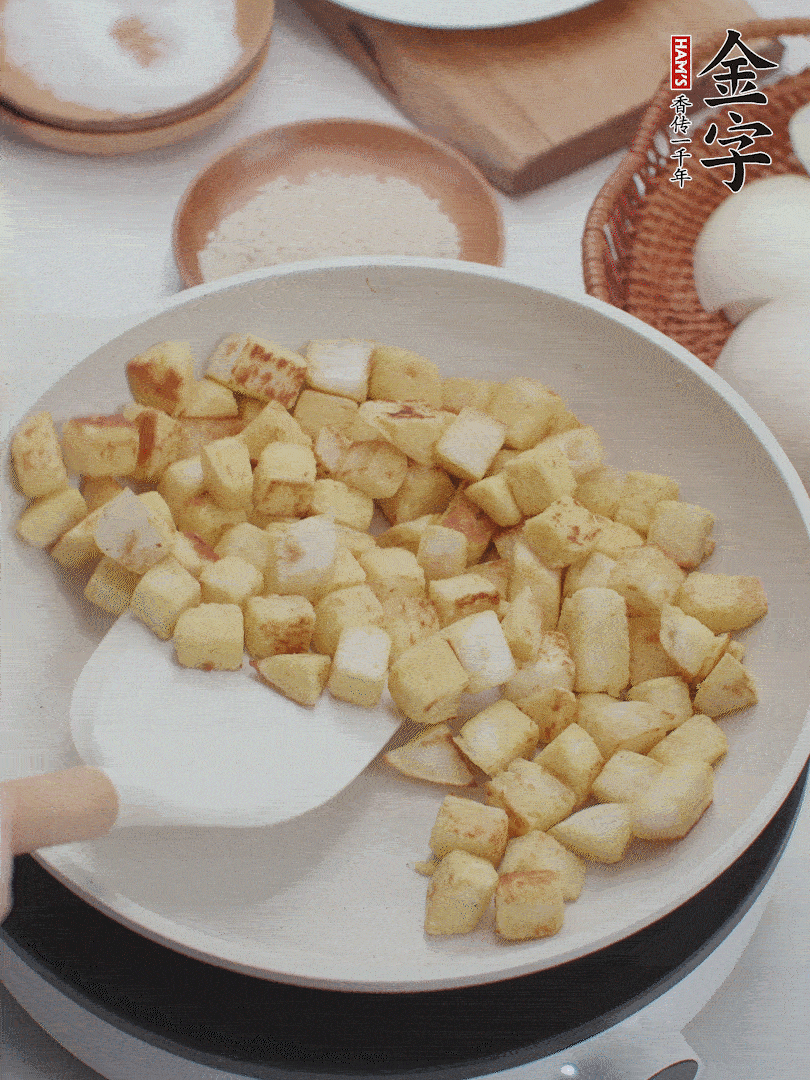 起鍋熱油，倒入饅頭丁，小火煎至蛋液凝固定型再翻面，饅頭丁部煎至金黃時(shí)盛起待用。
