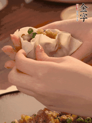 取一大勺餡料放進(jìn)餃子皮里，用大拇指按住頂部餡料，再用虎口掐出形狀。